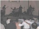 Seated, while the audience dances